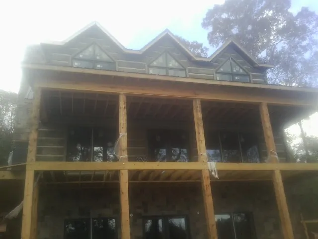 Dormers and porch framing on a large log home under construction — Roof Coating work by our crew in Pelzer