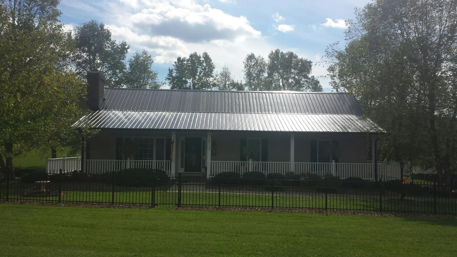 Gray metal roof on a brick ranch with a full width front porch — Gutter Guard Installation work by our crew in Pelzer